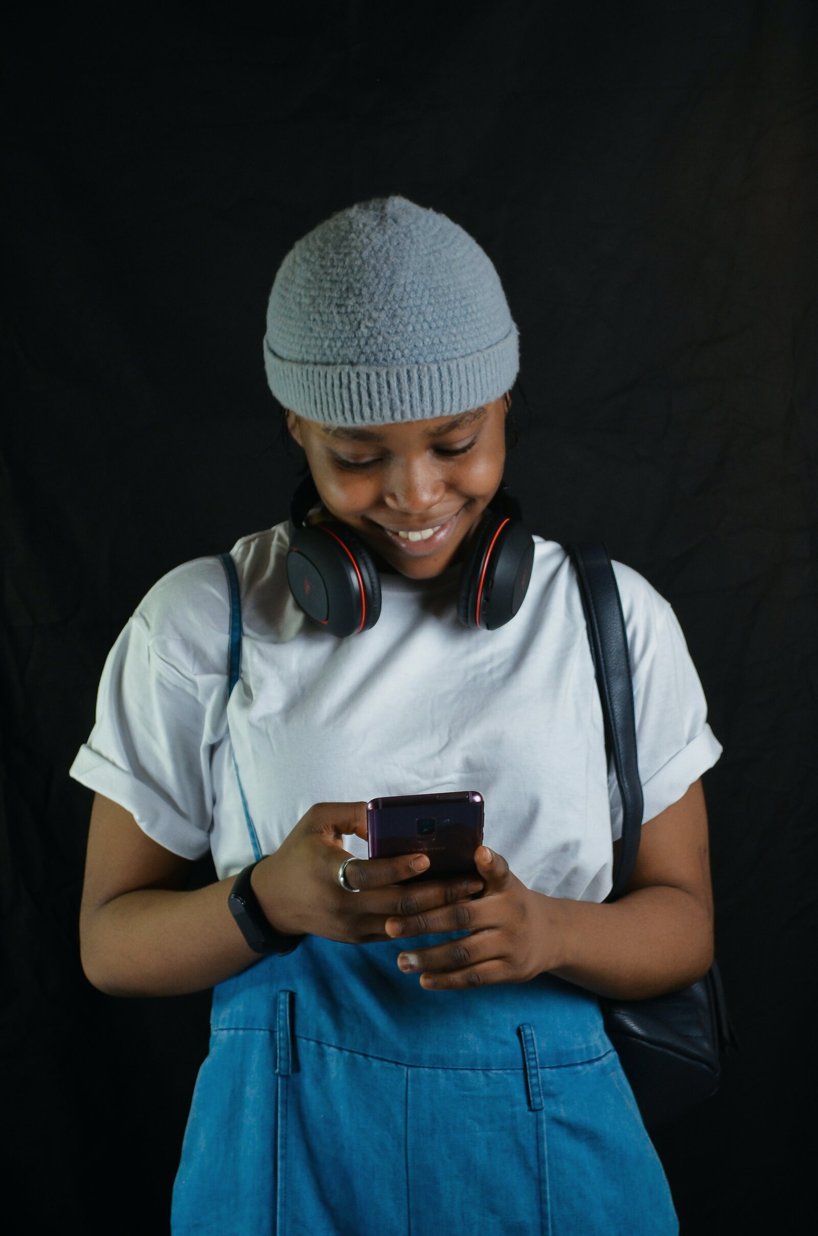 Temi, a young woman in a beanie and headphones, smiling at her phone